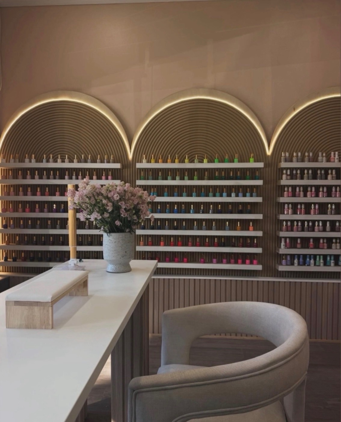 Arched, backlit polish wall stocked with hundreds of colors