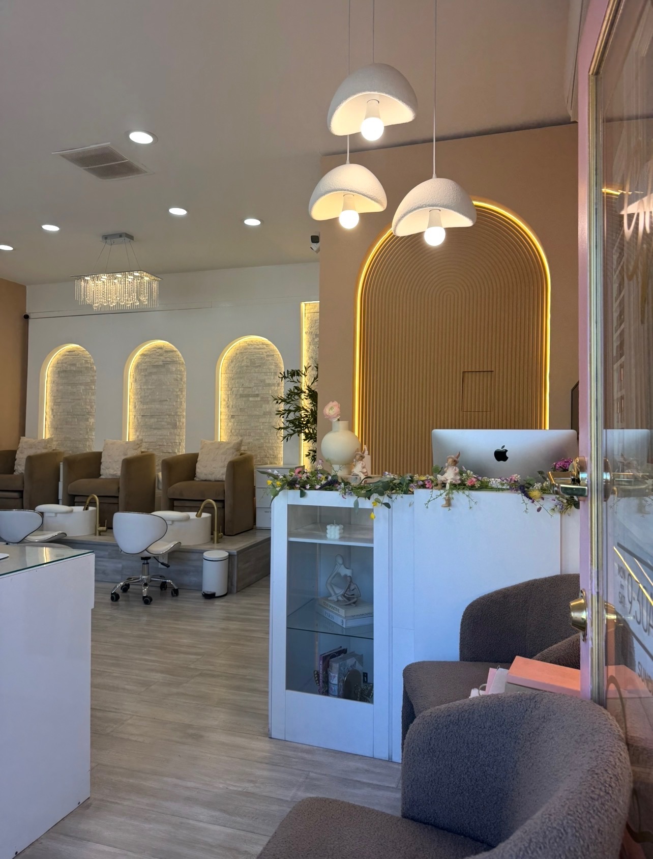 Inside Nail Bar Studio — pedicure lounge, arched lighting and a flower-topped reception desk